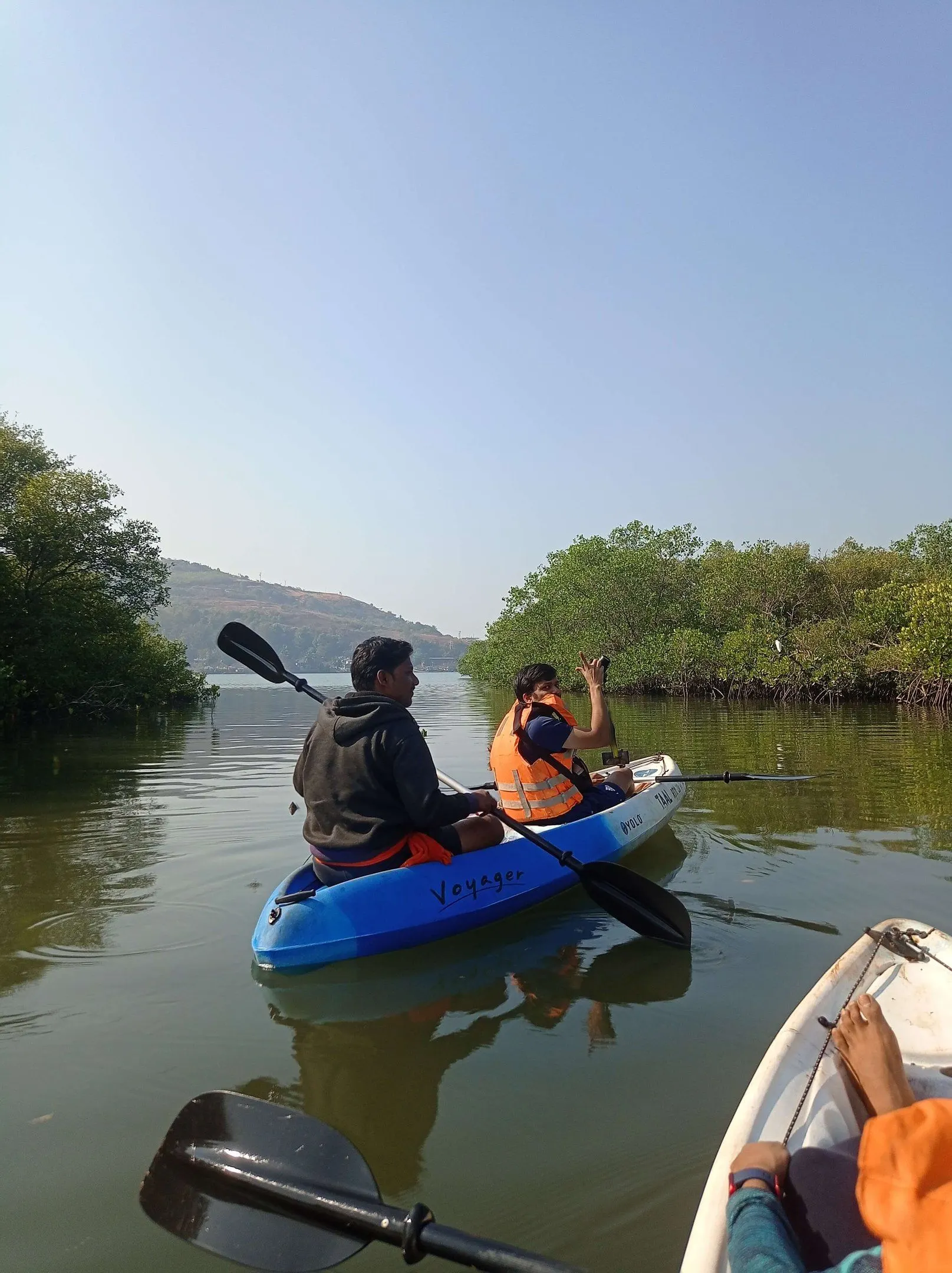 Two travellers kayaking through the green mangrove channels at Anjarle