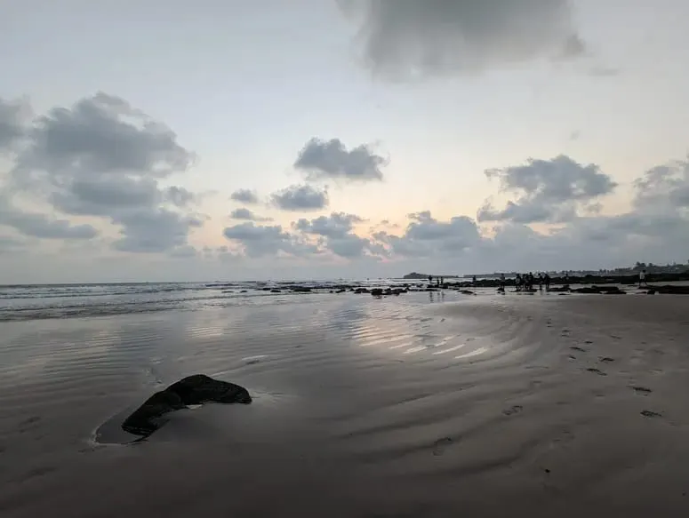Calm low-tide reflections at sunset on the flat sand of Karde Beach