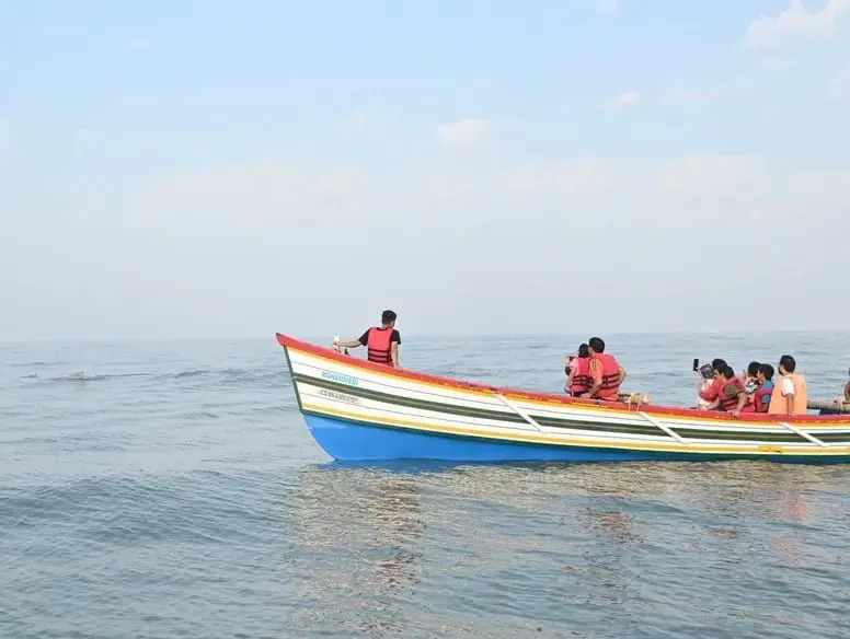 Tourists in life jackets on a traditional dolphin safari boat off the Dapoli coast