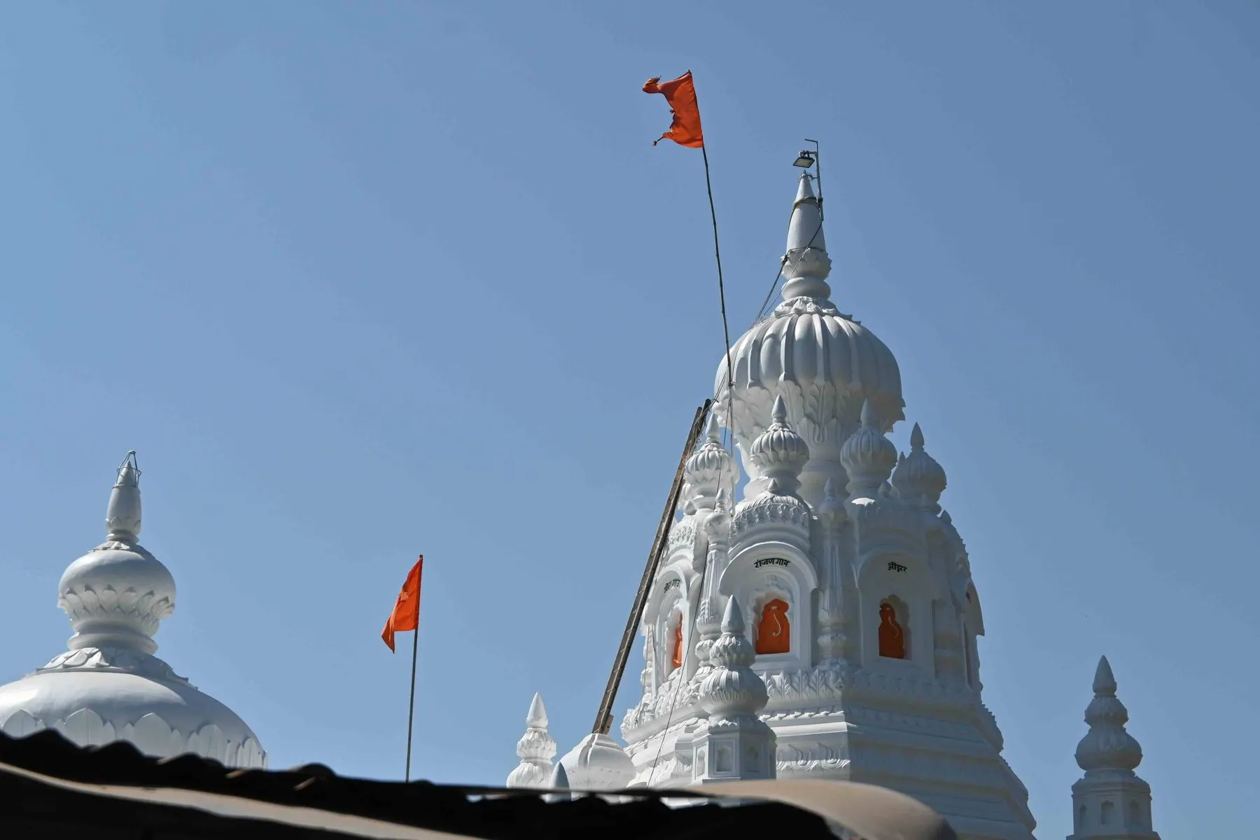 The white spire of the Kadyavarcha Ganpati temple against a blue sky in Anjarle